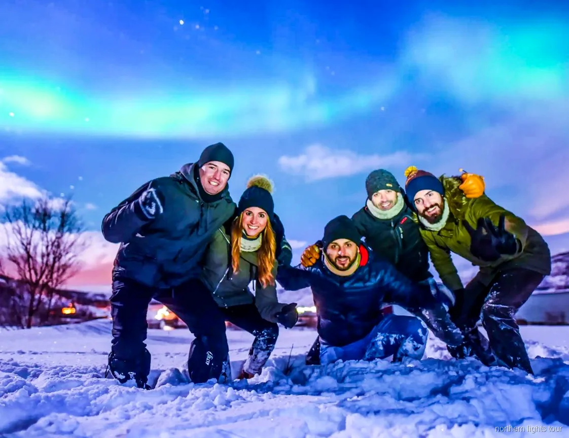 Grupo en la excursión de auroras boreales en Tromsø observando la aurora desde un campamento junto al autobús con calefacción