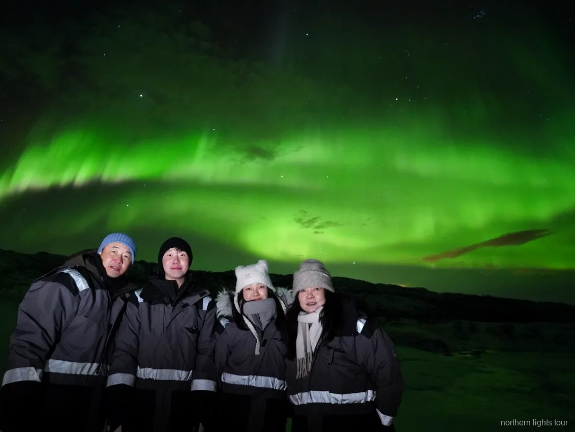 Voyageurs enveloppés dans des combinaisons thermiques sur le minibus de chasse aux aurores boréales de Tromsø