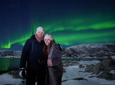 Grupo reduzido a observar a aurora boreal do tour de Tromsø a partir de um acampamento junto ao fiorde