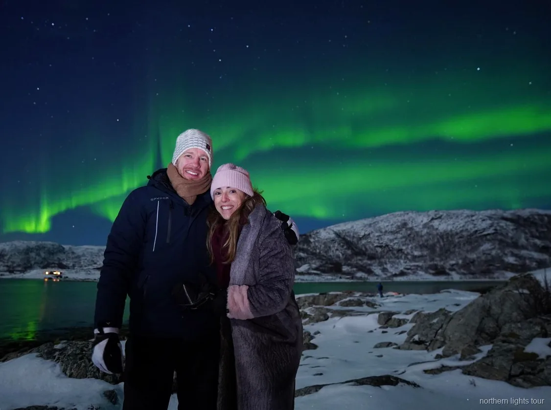 Grupo reduzido a observar a aurora boreal do tour de Tromsø a partir de um acampamento junto ao fiorde