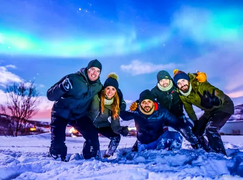 Grup a la safari d'aurora boreal de Tromsø observant l'aurora des d'un campament de bus climatitzat