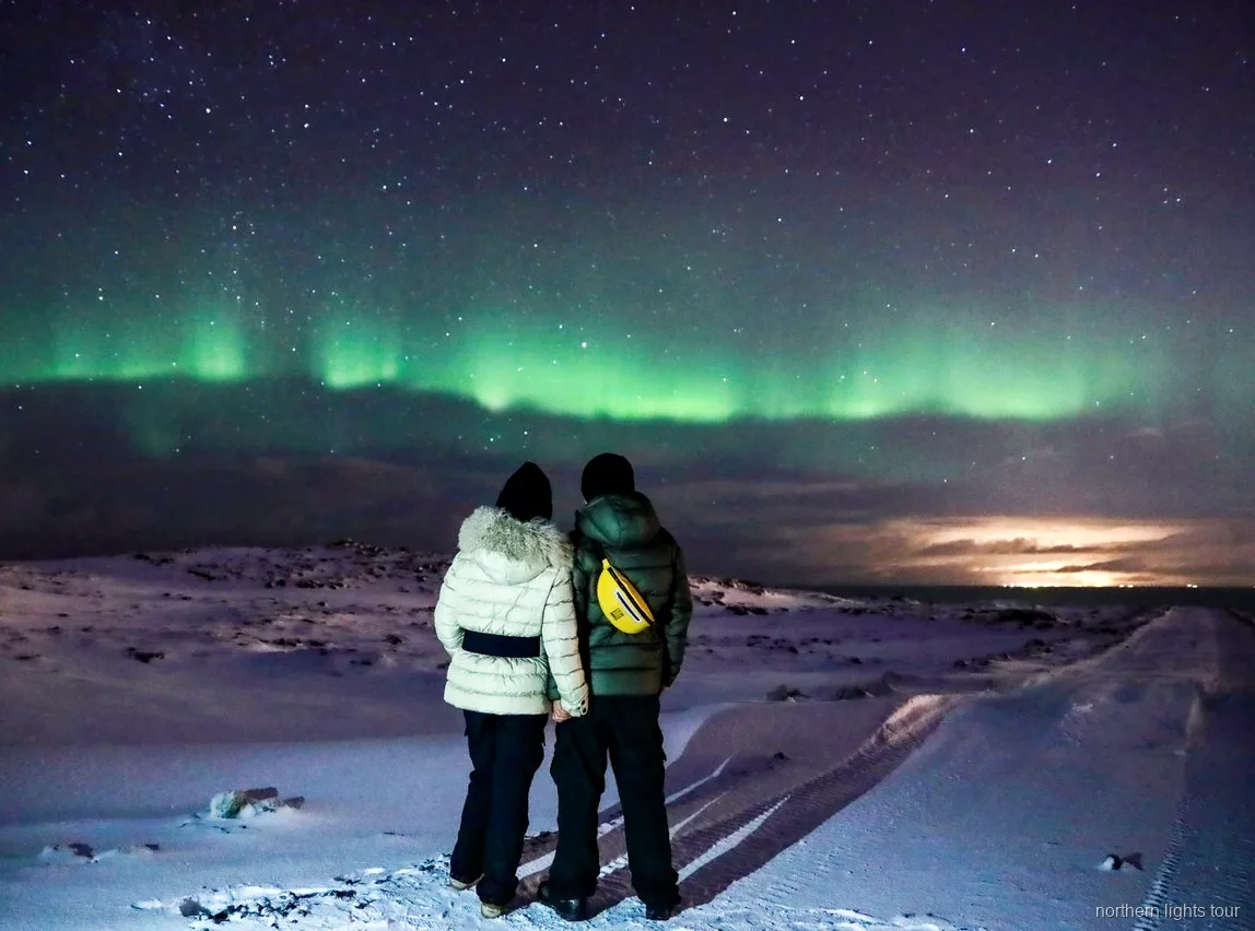 Ospiti che bevono cioccolata calda durante il tour aurora boreale Reykjavik in bus