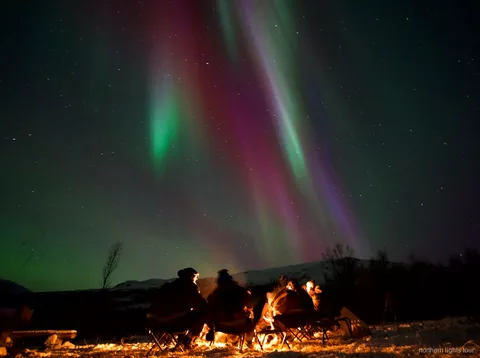 Tromsø kuzey ışıkları avı turunda gece bir Norveç fiyordu kenarında park edilmiş minibüs