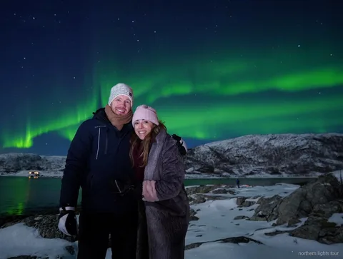 Kleine groep bekijkt het noorderlicht vanaf een fjordkamp op de Tromsø noorderlicht jacht tour