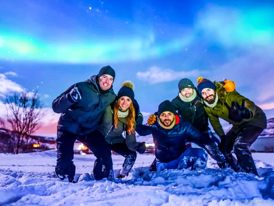 Groep op de Tromsø noorderlicht safari bekijkt het noorderlicht vanaf een verwarmd buskamp