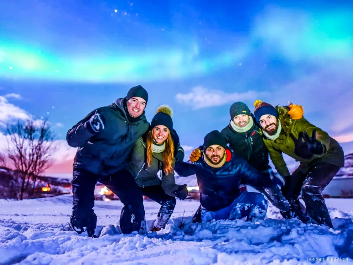 Gruppe på Tromsø nordlyssafari ser nordlyset fra en opvarmet buslejr